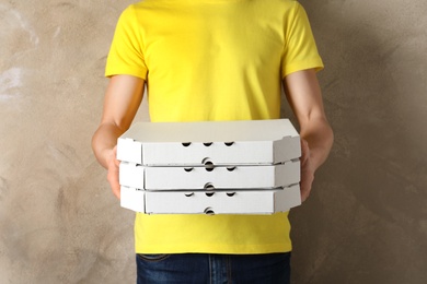 Young man with pizza boxes on color background. Food delivery service