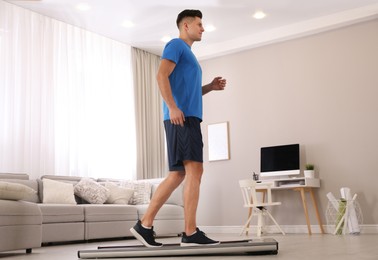 Photo of Sporty man training on walking treadmill at home