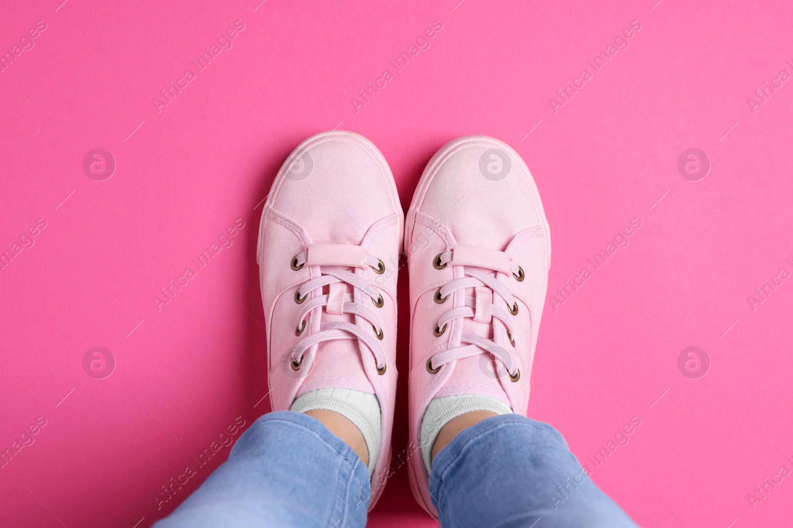 Photo of Woman in stylish sneakers standing on pink background, top view