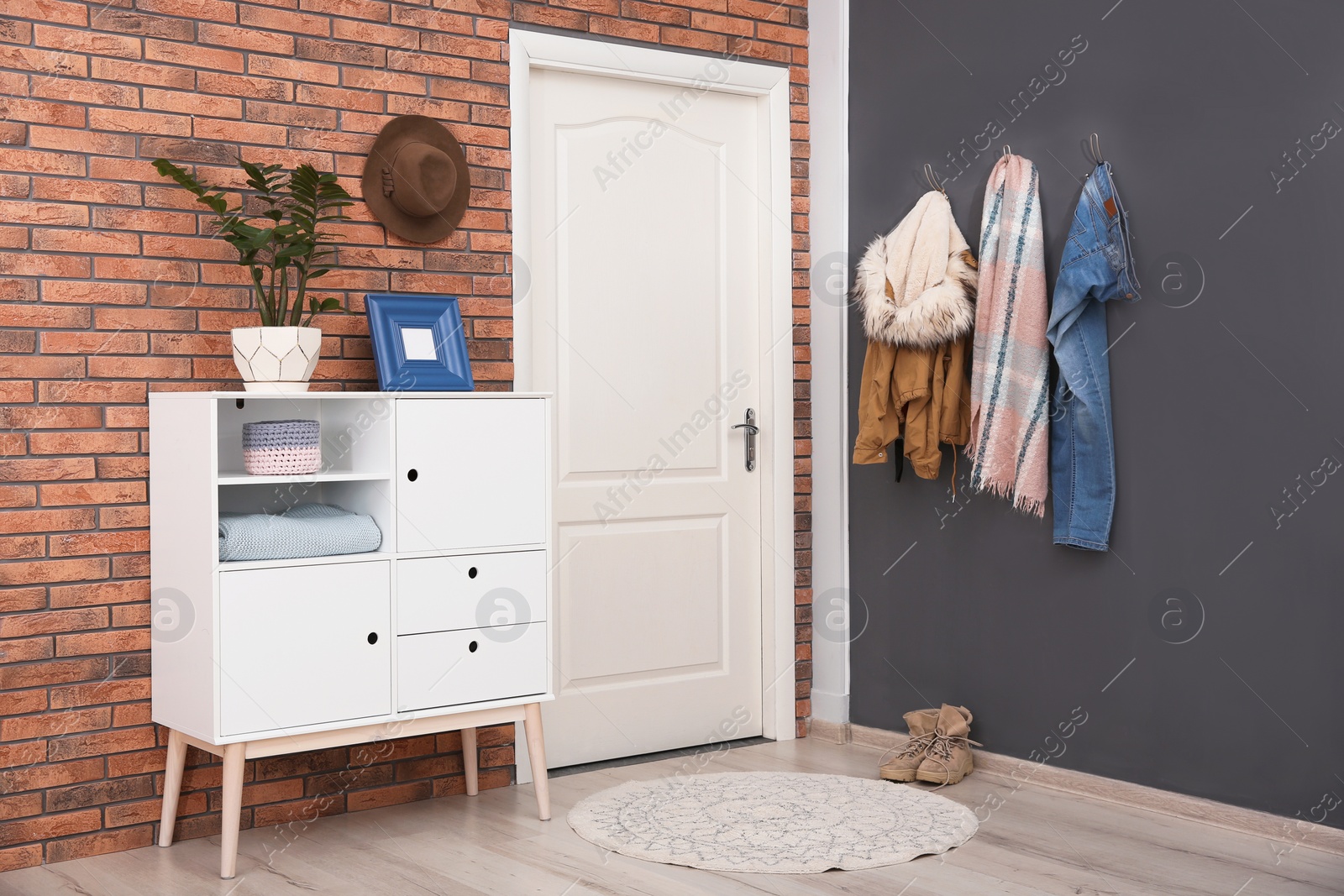 Photo of Modern hallway interior with stylish cabinet and clothes on wall