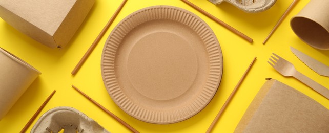 Image of Paper and wooden tableware on yellow background, flat lay. Banner design
