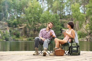 Young couple resting on pier near lake. Camping season