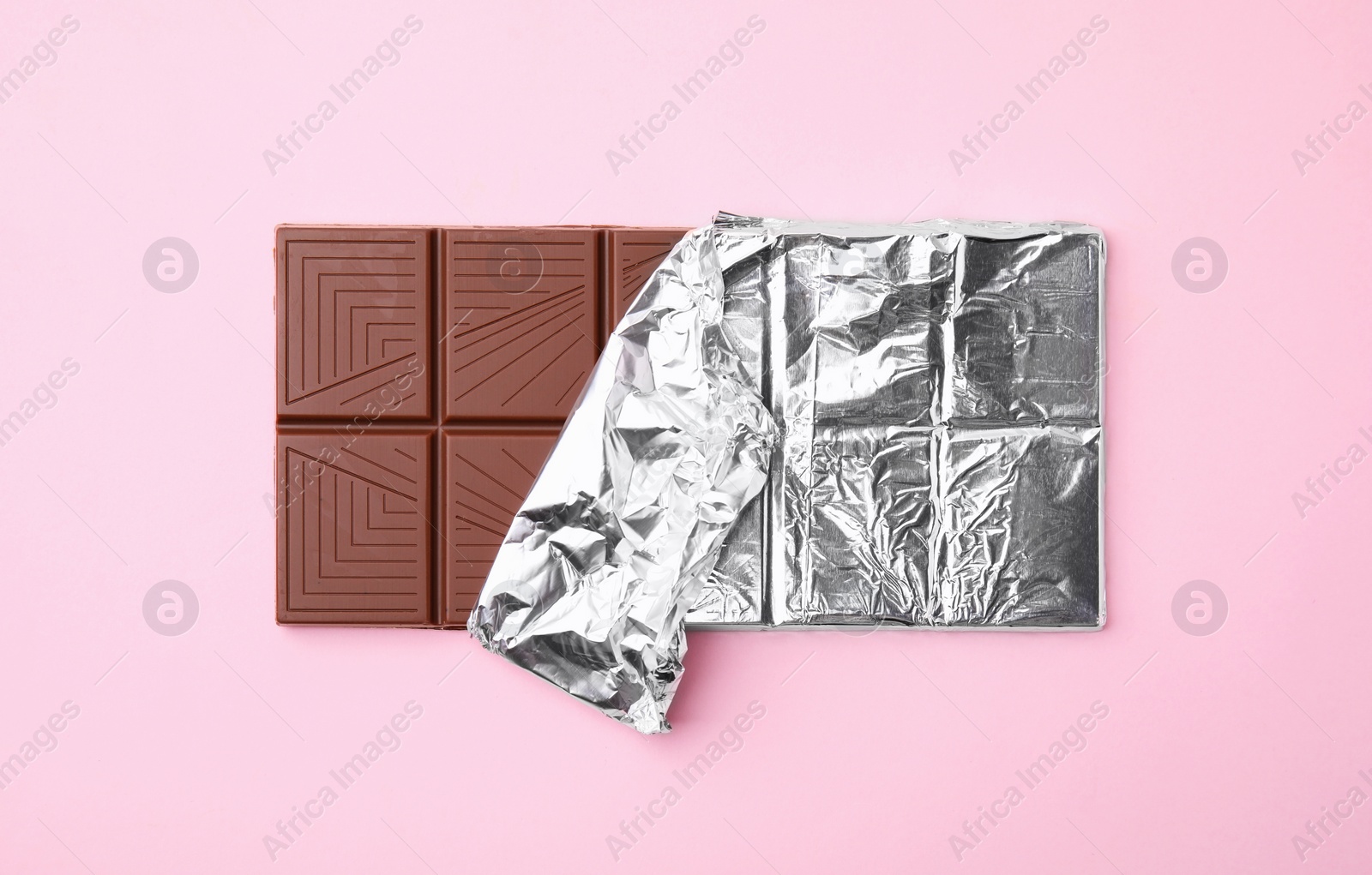 Photo of Tasty chocolate bar on pink background, top view