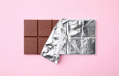 Tasty chocolate bar on pink background, top view