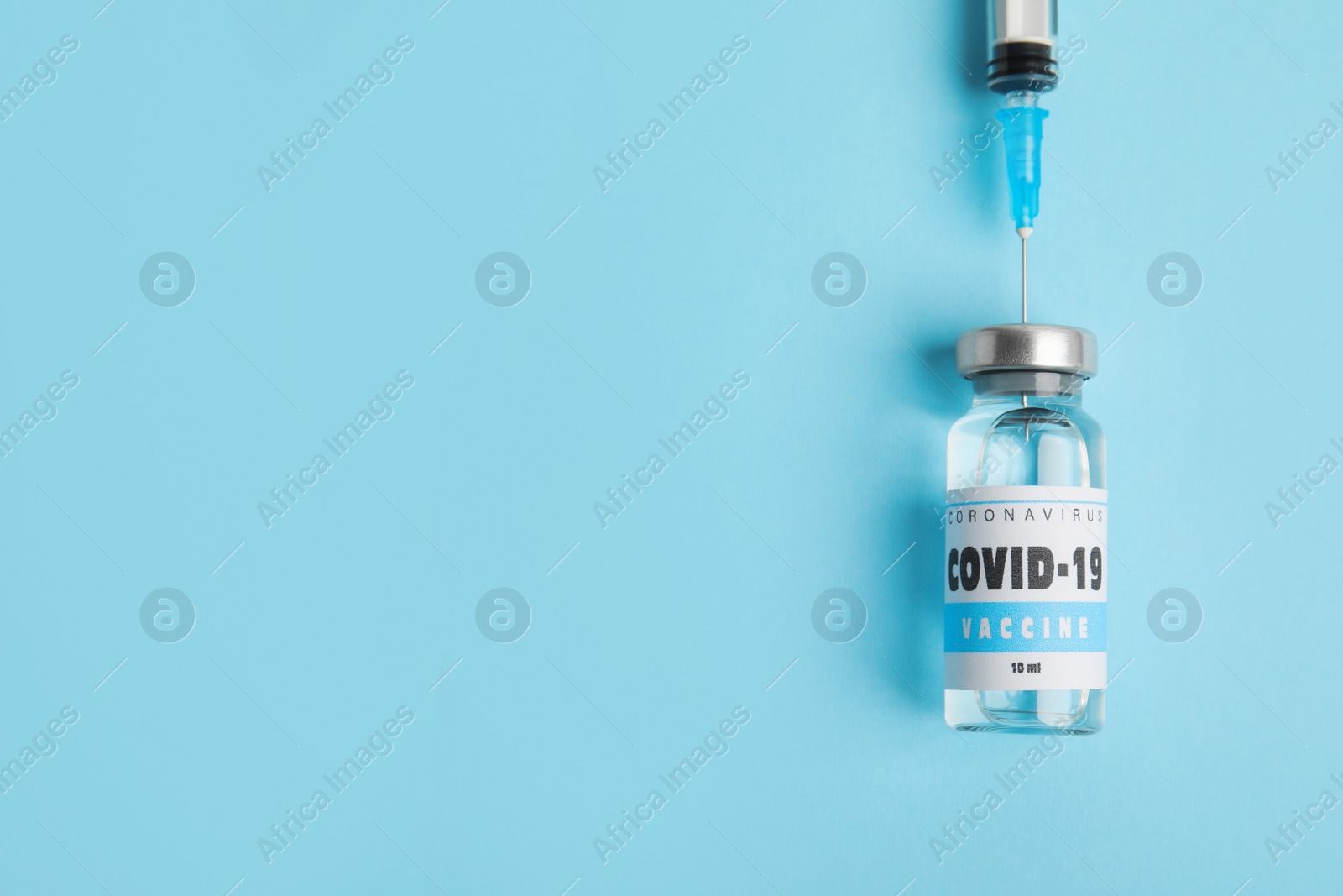 Photo of Filling syringe with coronavirus vaccine on light blue  background, flat lay. Space for text