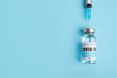 Filling syringe with coronavirus vaccine on light blue  background, flat lay. Space for text