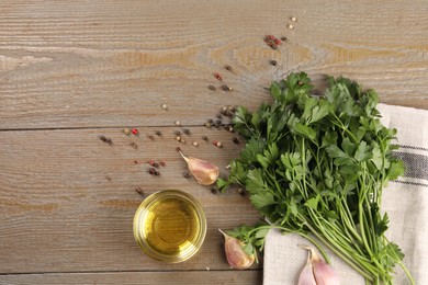 Bunch of raw parsley, oil, garlic and peppercorns on wooden table, flat lay. Space for text