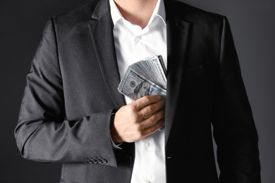 Man putting bribe money into pocket on black background, closeup