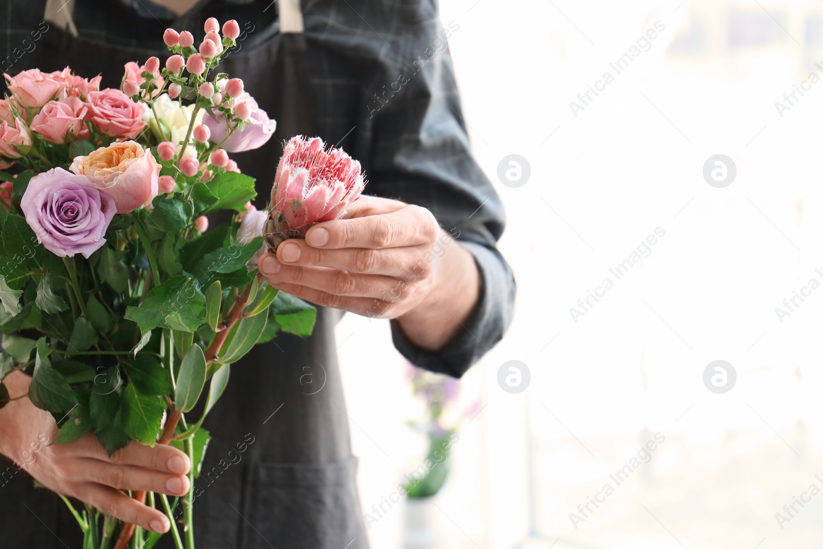 Photo of Male florist holding beautiful bouquet, closeup