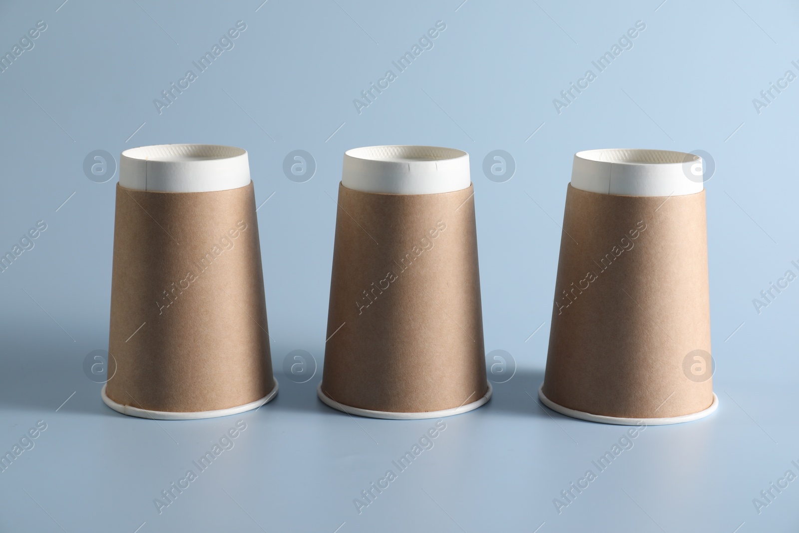 Photo of Shell game. Three paper cups on light blue background