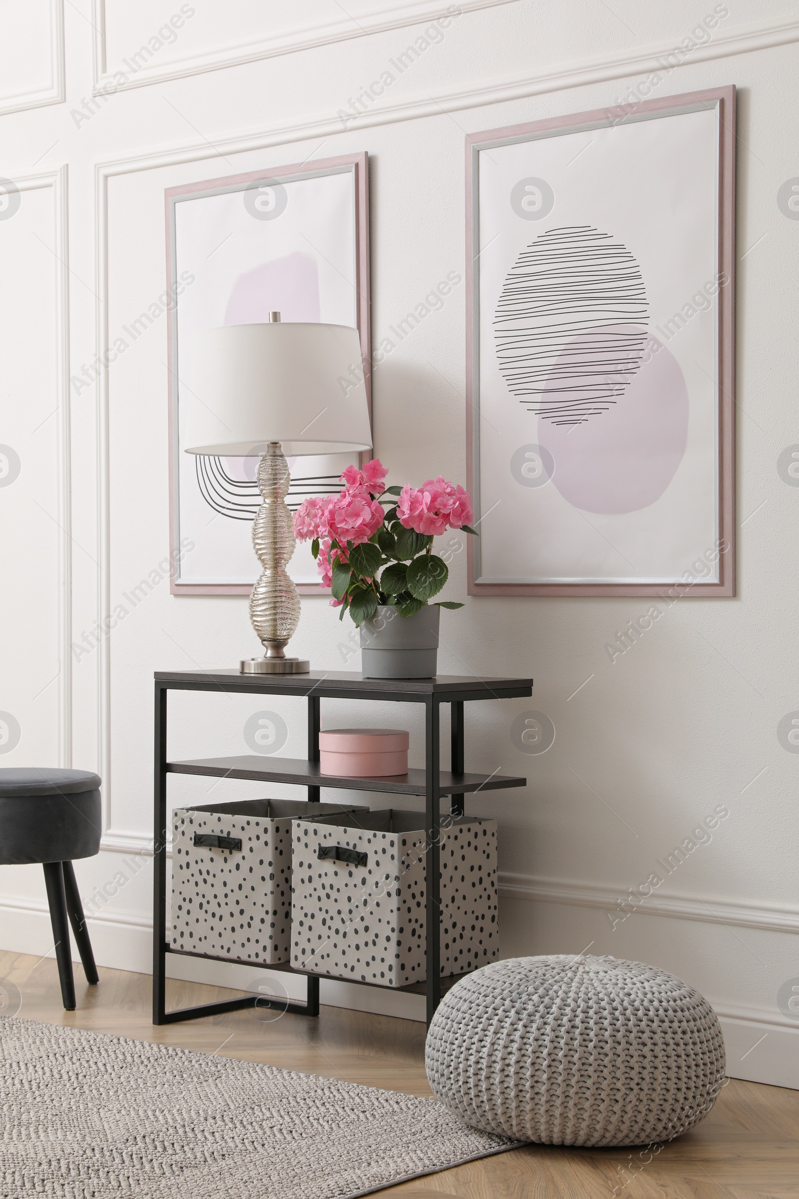 Photo of Console table with beautiful hydrangea flower and lamp near white wall in hallway. Interior design