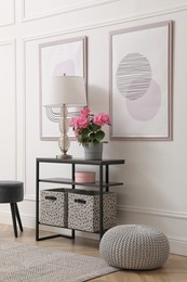 Photo of Console table with beautiful hydrangea flower and lamp near white wall in hallway. Interior design