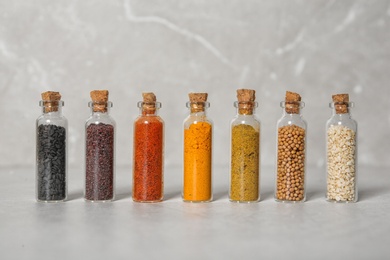 Photo of Row of small glass bottles with different spices on color background