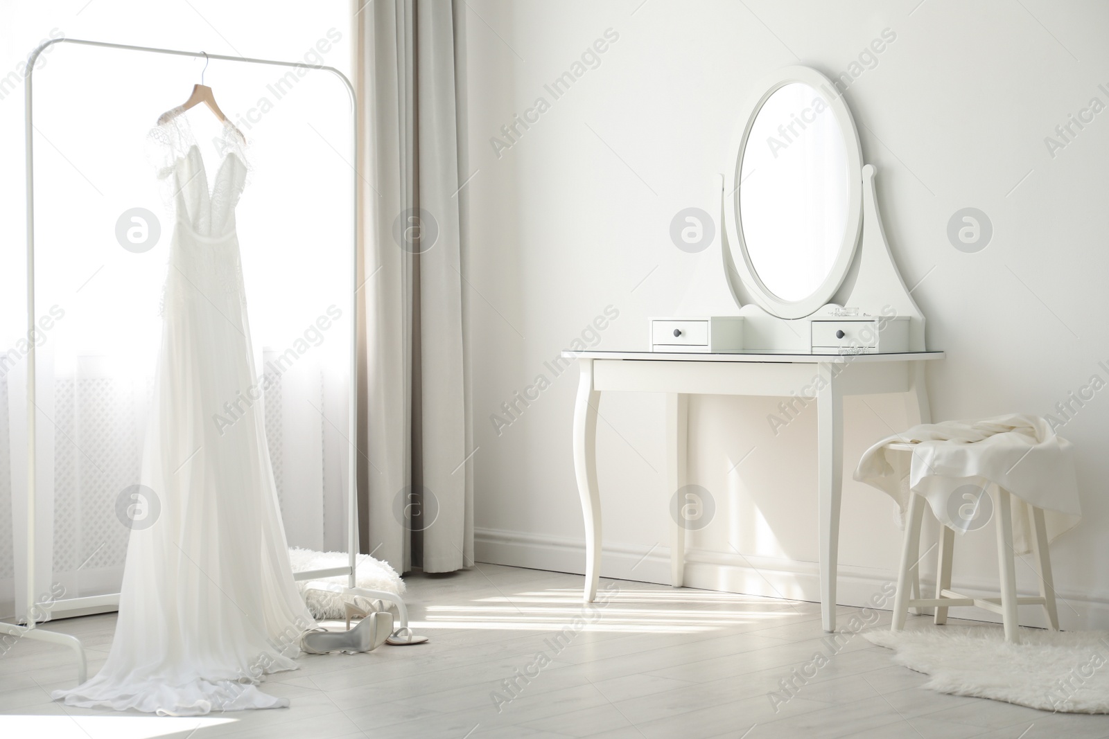 Photo of Beautiful wedding dress hanging on clothing rack in room