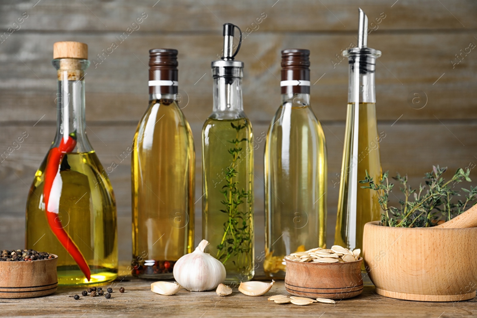 Photo of Different cooking oils in bottles on wooden table