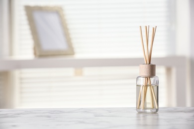 Photo of Aromatic reed air freshener on white table at home, space for text