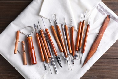 Photo of Set of different clay crafting tools on wooden table, top view