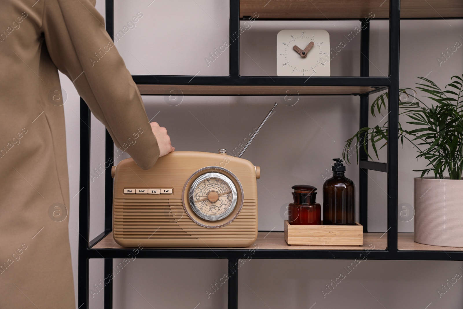 Photo of Woman turning volume knob on radio indoors, closeup