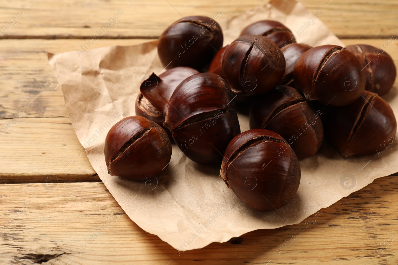 Photo of Fresh edible sweet chestnuts on wooden table, closeup