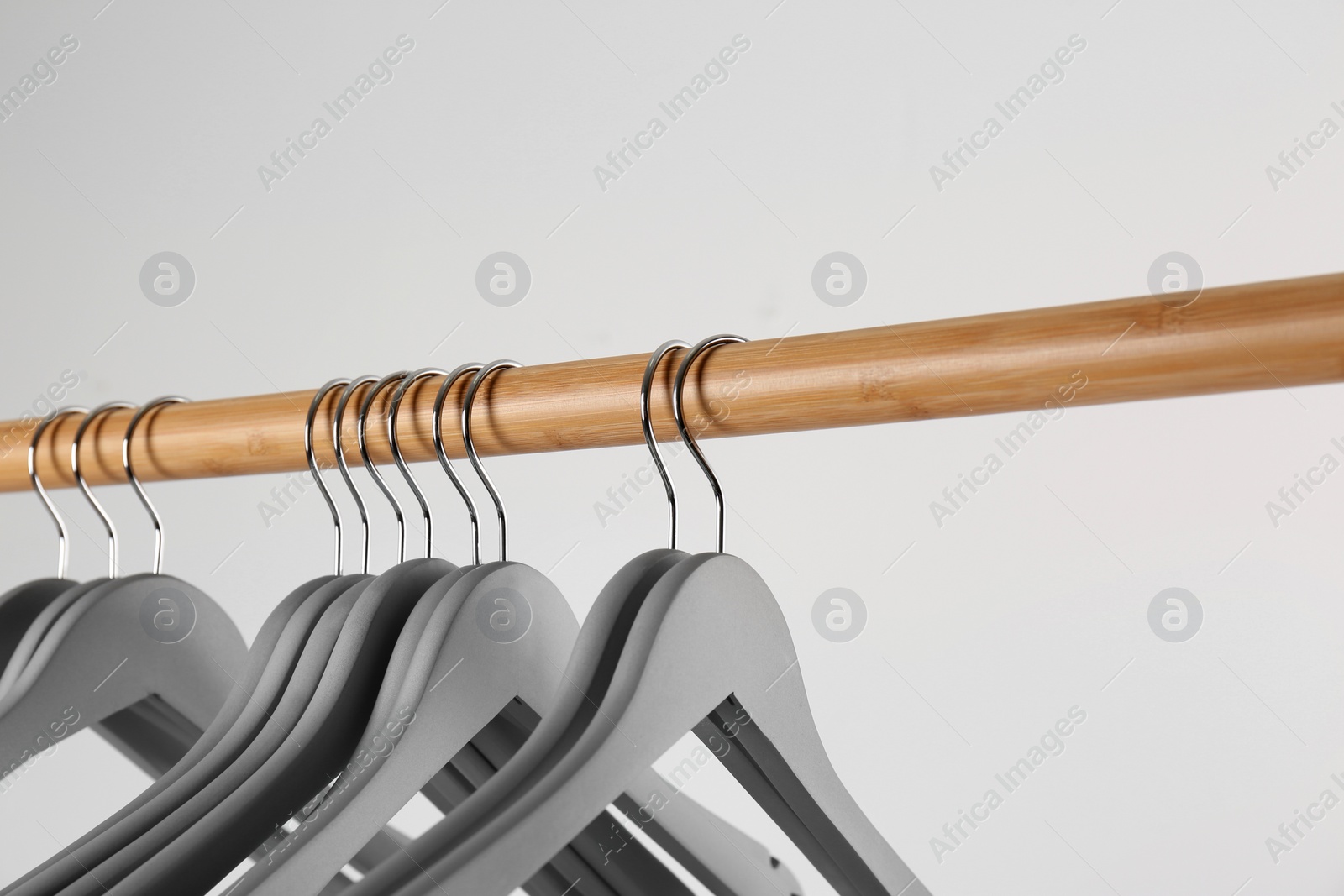 Photo of Wooden rack with clothes hangers on white background, closeup