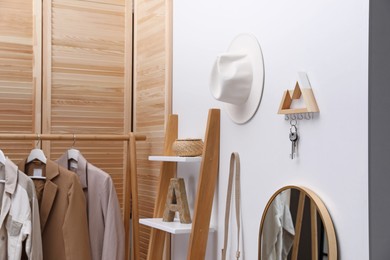 Photo of Modern hallway with stylish furniture, accessories and wooden hanger for keys on white wall. Interior design