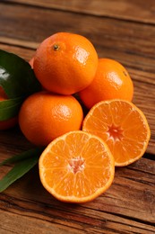 Fresh tangerines with green leaves on wooden table