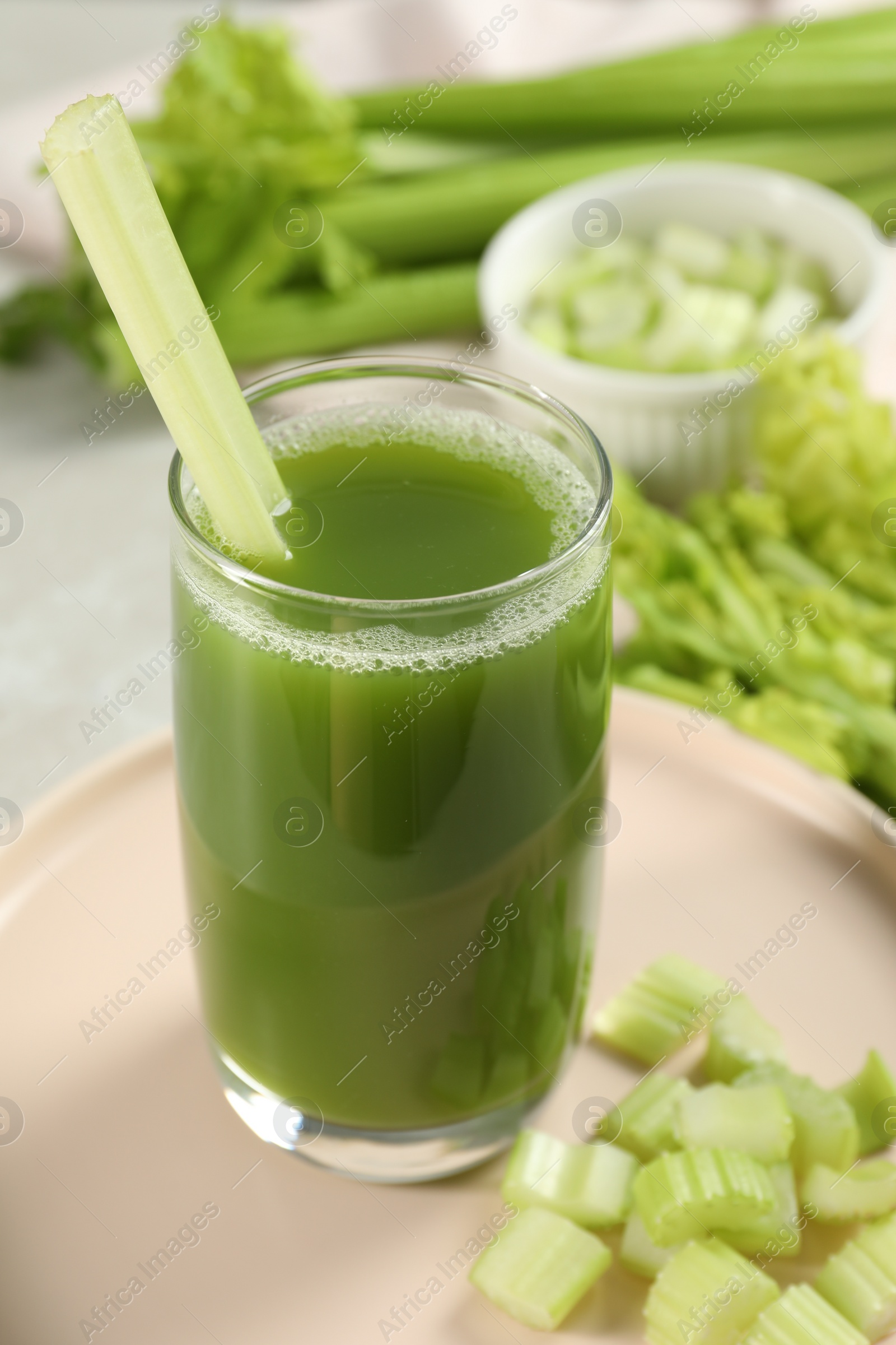 Photo of Glass of delicious celery juice and vegetables on table, closeup