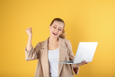 Portrait of emotional young woman with laptop on yellow background