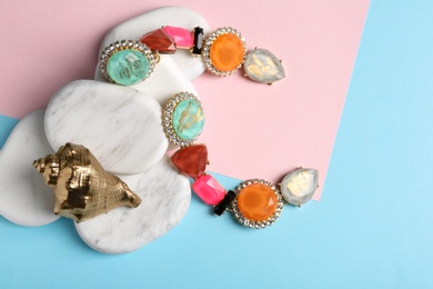 Photo of Stylish earrings, white marble stones and decorative shell on color background, flat lay. Luxury jewelry