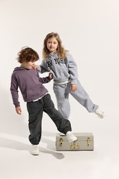 Photo of Fashion concept. Stylish children with vintage suitcase on white background