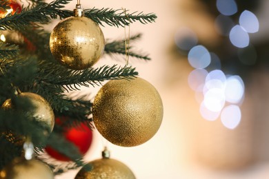Photo of Christmas tree decorated with festive balls on light background, closeup. Space for text