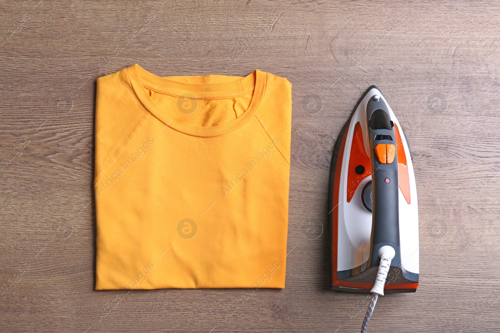 Photo of Flat lay composition with folded clothes and iron on wooden table