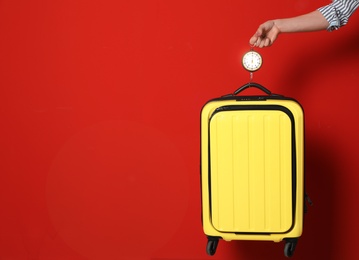 Woman weighing suitcase against color background, closeup. Space for text