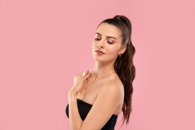Photo of Beautiful woman with elegant jewelry on pink background, space for text