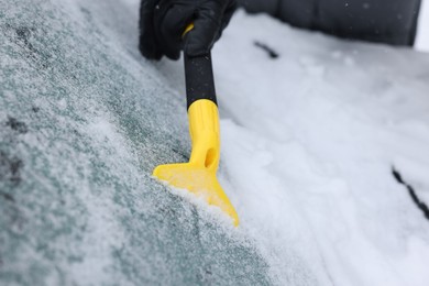 Photo of Man cleaning snow from car windshield outdoors, closeup