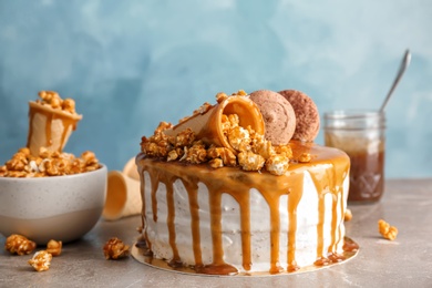 Photo of Delicious homemade cake with caramel sauce and popcorn on table