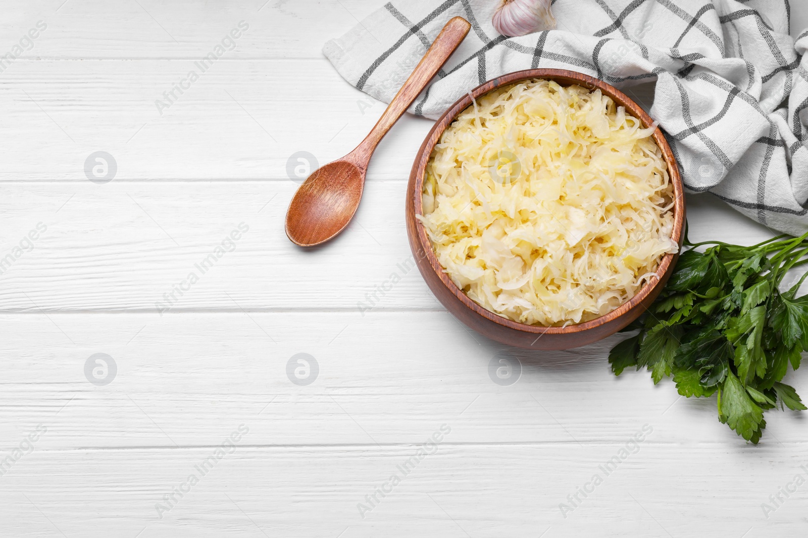 Photo of Bowl of tasty sauerkraut and parsley on white wooden, flat lay. Space for text