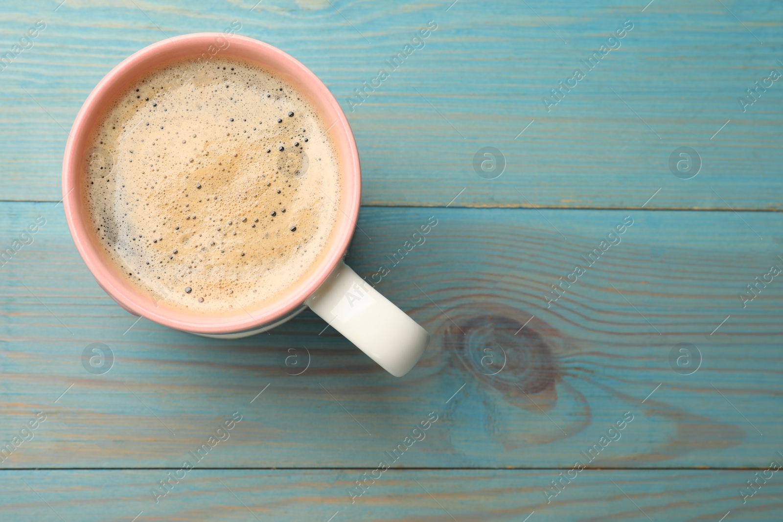 Photo of Cup of aromatic coffee on light blue wooden table, top view. Space for text