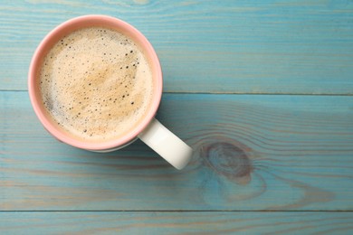 Cup of aromatic coffee on light blue wooden table, top view. Space for text