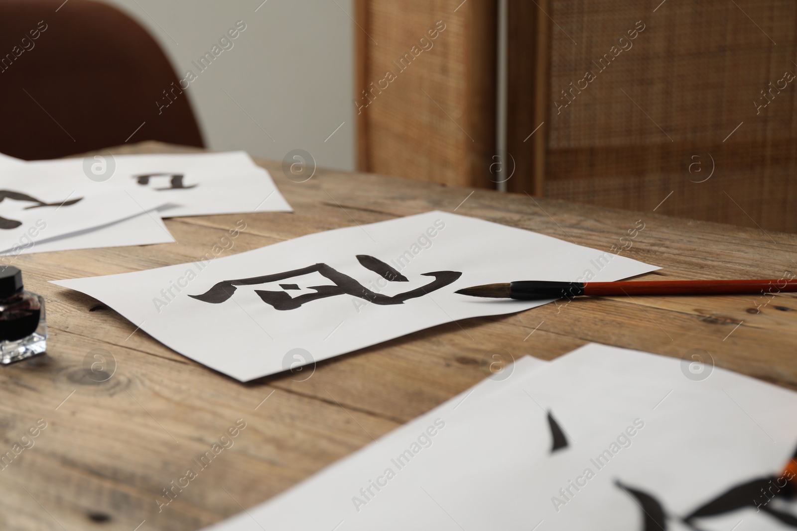 Photo of Calligraphy. Papers with written hieroglyphs and brush on wooden table