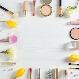 Photo of Flat lay composition with different decorative cosmetics and flowers on wooden table, space for text. Trendy makeup products