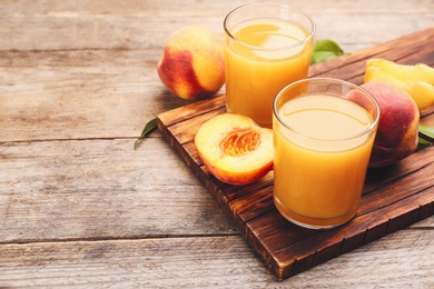 Photo of Natural peach juice and fresh fruits on wooden table. Space for text