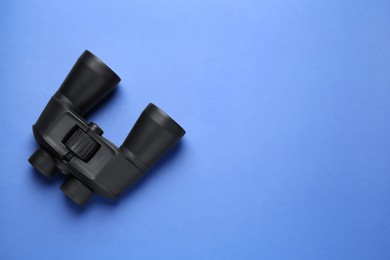 Modern binoculars on blue background, top view. Space for text