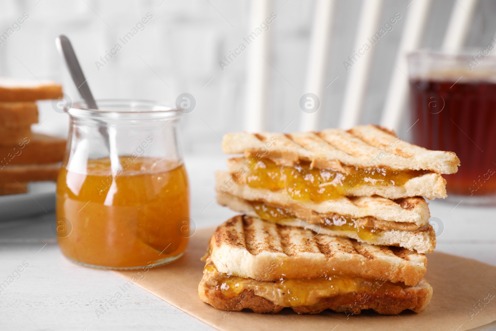 Image of Tasty sandwiches with apricot jam and peanut butter for breakfast on white table
