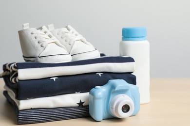 Photo of Baby clothes, shoes and toy camera on wooden table, closeup