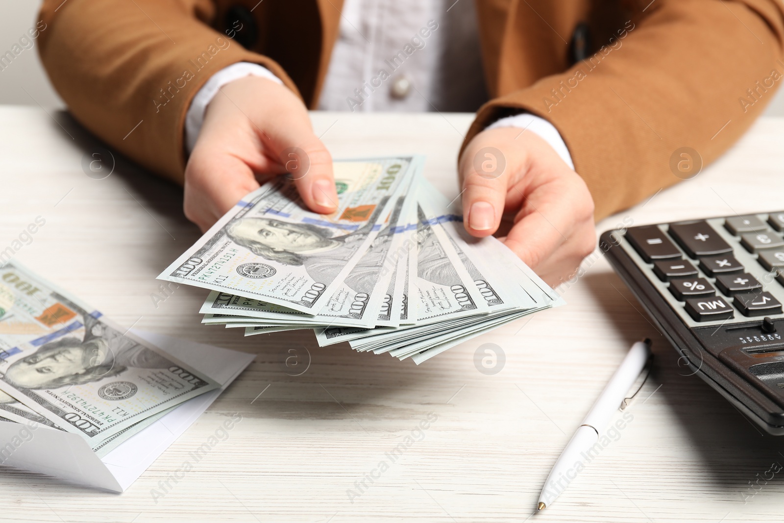 Photo of Money exchange. Woman holding dollar banknotes at white wooden table, closeup