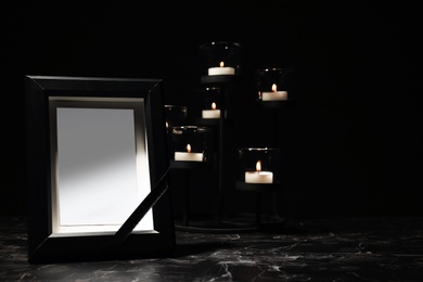 Photo of Funeral photo frame and burning candles in holder on dark background