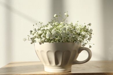 Photo of Beautiful gypsophila in white cup on wooden table