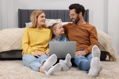 Happy family with laptop on floor at home