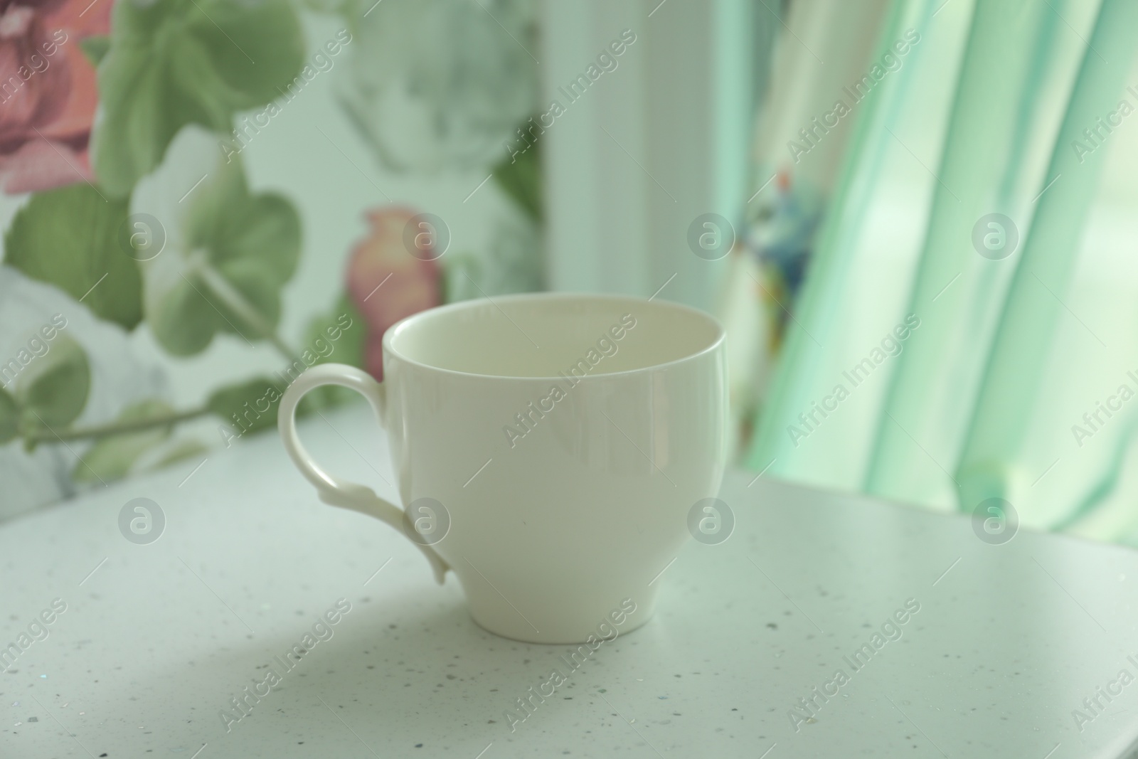 Photo of Empty cup on white table indoors, closeup